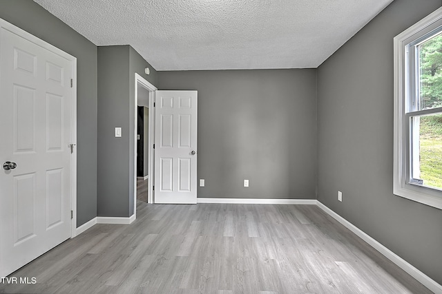 unfurnished bedroom featuring a textured ceiling and light hardwood / wood-style flooring