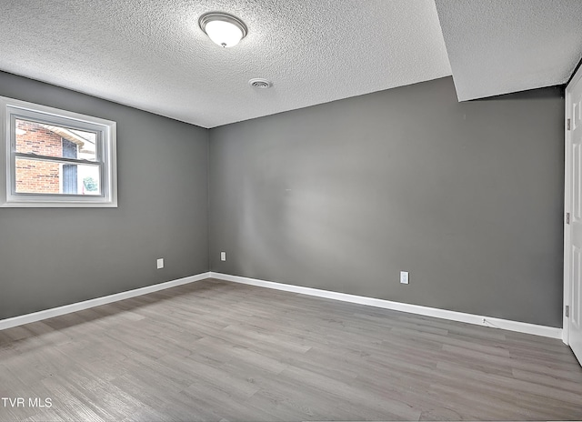 unfurnished room featuring a textured ceiling and light wood-type flooring