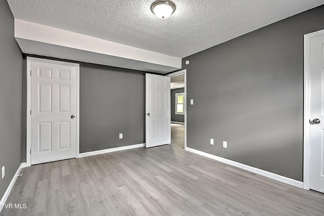 unfurnished bedroom with light hardwood / wood-style flooring and a textured ceiling