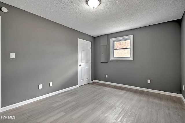 spare room with light hardwood / wood-style floors and a textured ceiling