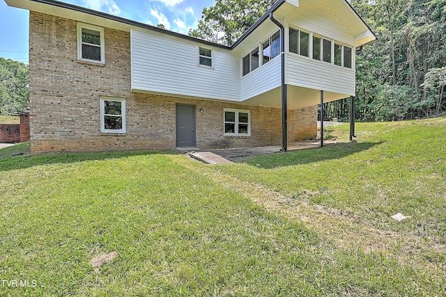 back of property with a sunroom, a patio area, and a yard