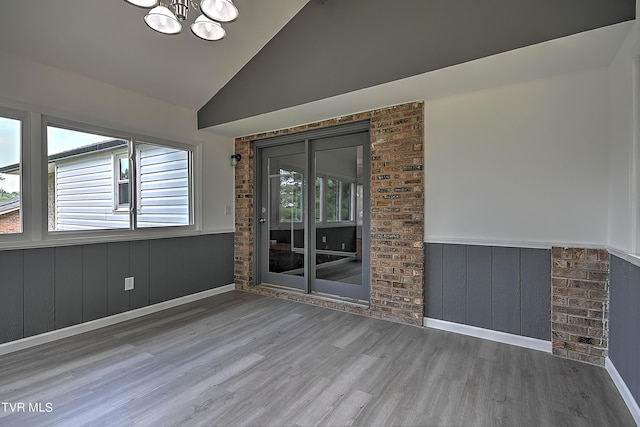 empty room with hardwood / wood-style flooring, high vaulted ceiling, and a notable chandelier