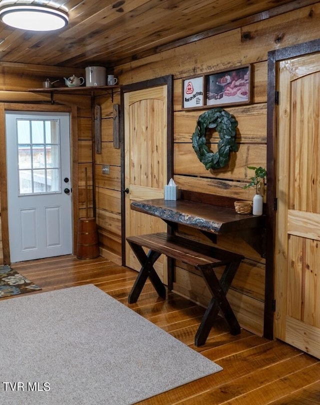 foyer entrance with wood walls, dark hardwood / wood-style floors, and wood ceiling