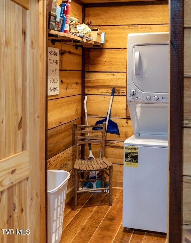 laundry room featuring wooden walls and stacked washer / drying machine