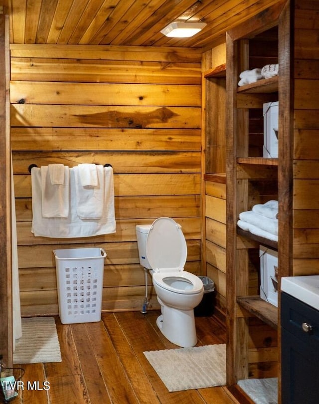 bathroom with toilet, hardwood / wood-style flooring, wooden ceiling, wooden walls, and vanity