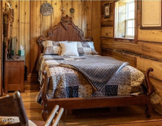 bedroom featuring wooden walls and hardwood / wood-style flooring