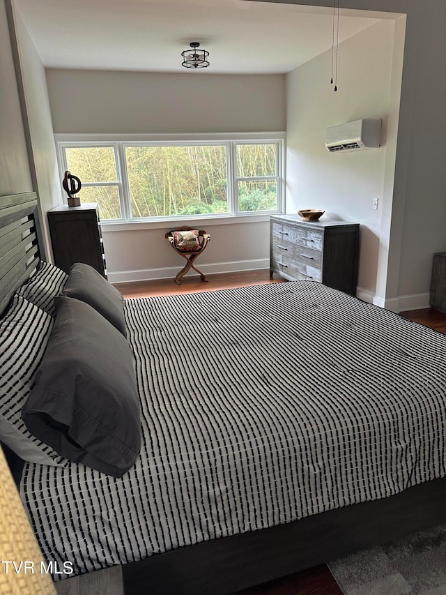 bedroom with hardwood / wood-style floors and a wall unit AC