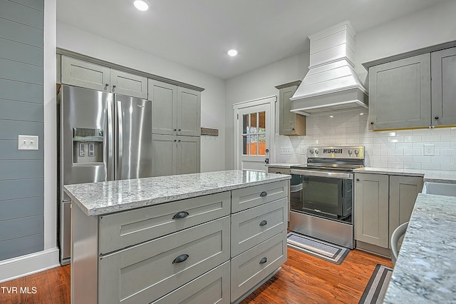 kitchen featuring light stone countertops, custom range hood, stainless steel appliances, and gray cabinets