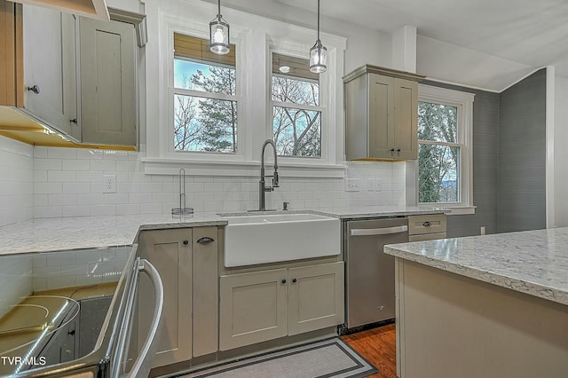 kitchen featuring stove, light stone counters, stainless steel dishwasher, gray cabinetry, and sink