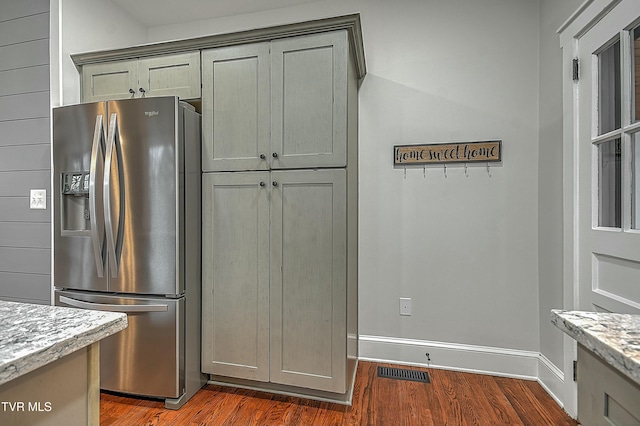 kitchen featuring light stone countertops, stainless steel refrigerator with ice dispenser, and dark hardwood / wood-style flooring