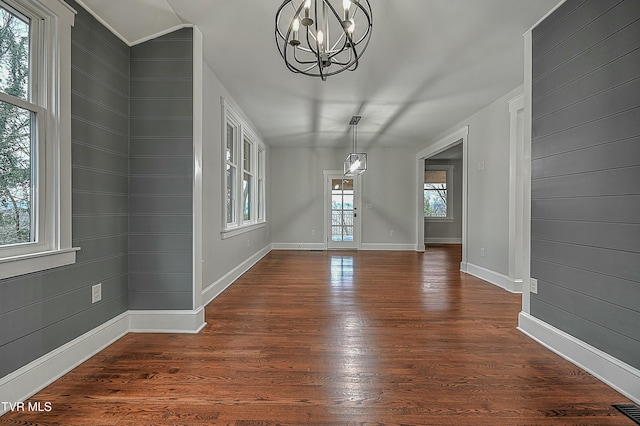 unfurnished dining area featuring vaulted ceiling, a wealth of natural light, dark hardwood / wood-style floors, and a notable chandelier