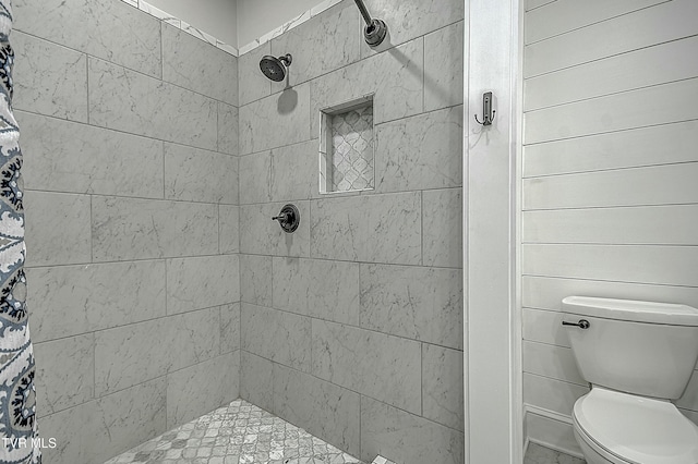 bathroom with a tile shower and toilet