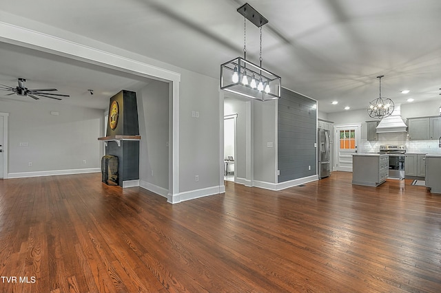 interior space with ceiling fan with notable chandelier, a fireplace, and dark wood-type flooring