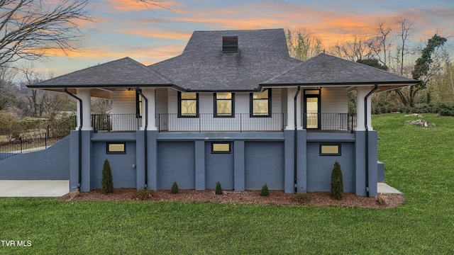 back house at dusk featuring a porch and a lawn