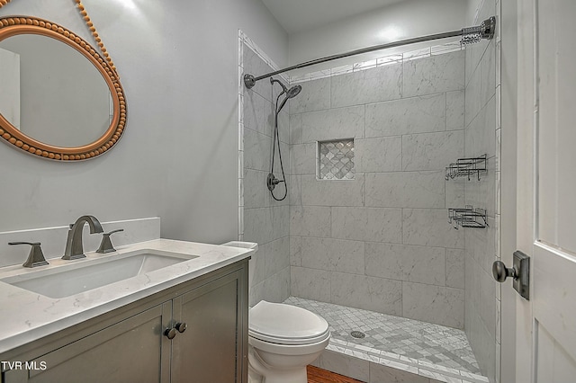 bathroom with tiled shower, vanity, and toilet