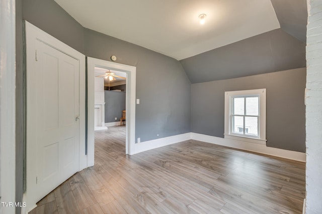 spare room featuring ceiling fan, lofted ceiling, and light wood-type flooring