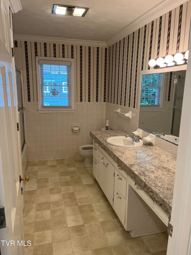 bathroom with crown molding, tile floors, tile walls, vanity, and toilet