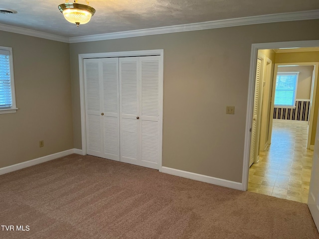 unfurnished bedroom with a closet, ornamental molding, and carpet floors