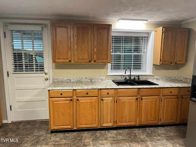 kitchen with sink, crown molding, and dark tile floors