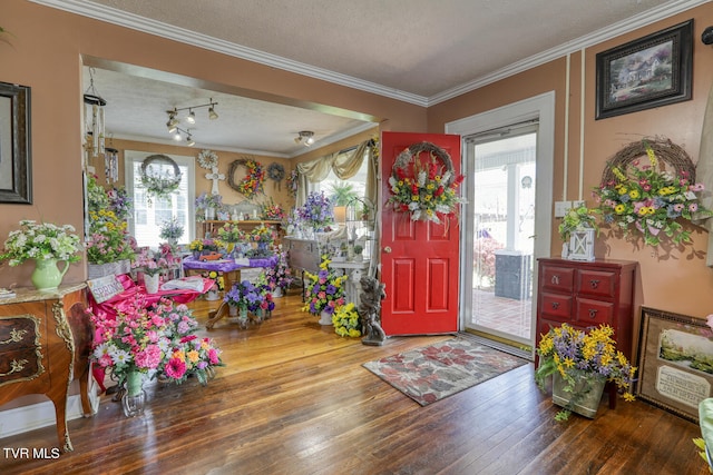 foyer entrance with a textured ceiling, ornamental molding, track lighting, and hardwood / wood-style floors