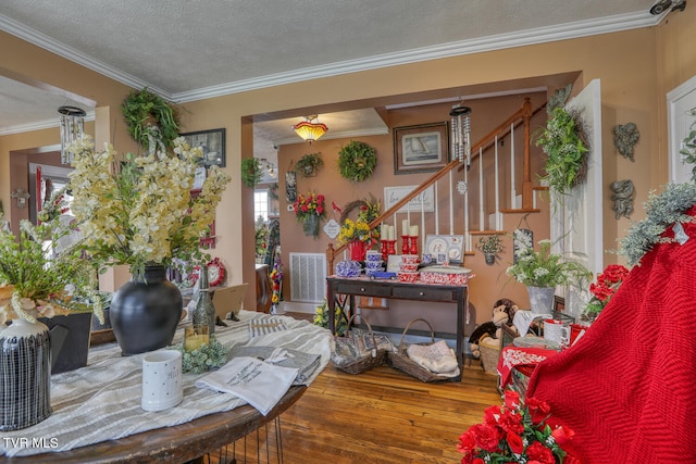 interior space featuring a textured ceiling, ornamental molding, and hardwood / wood-style floors