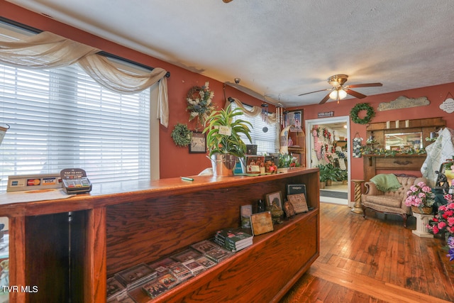 interior space with a textured ceiling, ceiling fan, a healthy amount of sunlight, and hardwood / wood-style floors