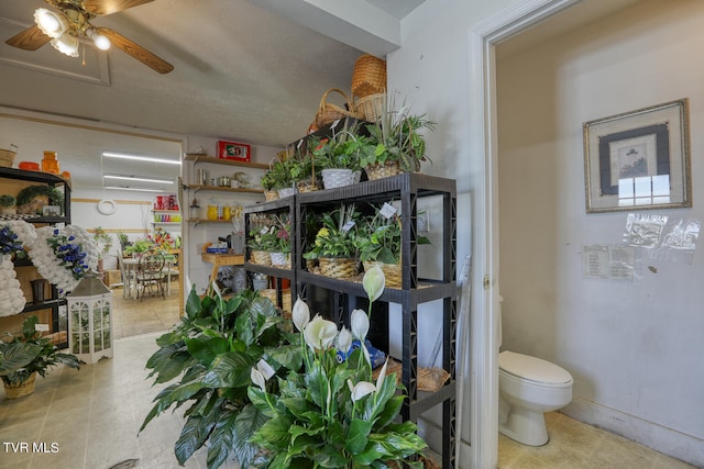 interior space with a wall mounted AC, tile flooring, ceiling fan, and toilet