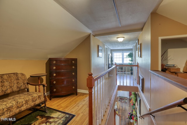 interior space with light hardwood / wood-style floors, a textured ceiling, and lofted ceiling