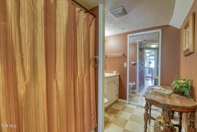 bathroom featuring a textured ceiling, tile flooring, vanity, and toilet