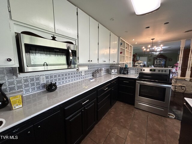 kitchen with tasteful backsplash, decorative light fixtures, dark tile patterned floors, stainless steel appliances, and white cabinets