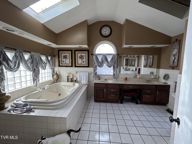 bathroom with tile patterned flooring, vanity, a wealth of natural light, and tiled tub