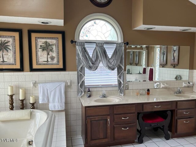 bathroom with tile patterned flooring, vanity, a bath, and tile walls