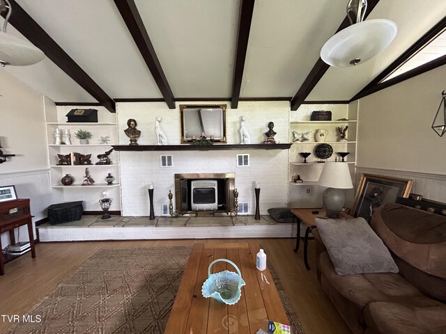 living room featuring built in features, wood-type flooring, lofted ceiling with beams, and a wood stove