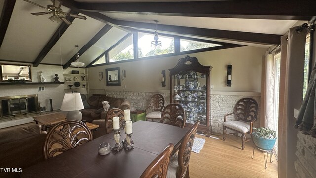 dining room with vaulted ceiling with beams, a fireplace, light hardwood / wood-style floors, and ceiling fan