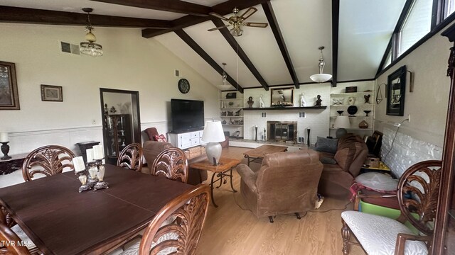 dining space featuring ceiling fan, light hardwood / wood-style flooring, high vaulted ceiling, and beamed ceiling