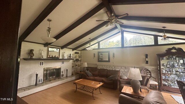 living room featuring hardwood / wood-style flooring, ceiling fan, lofted ceiling with beams, and a brick fireplace