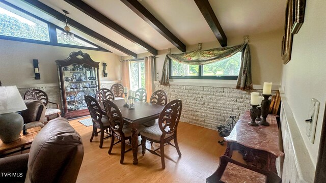 dining room with lofted ceiling with beams and light wood-type flooring