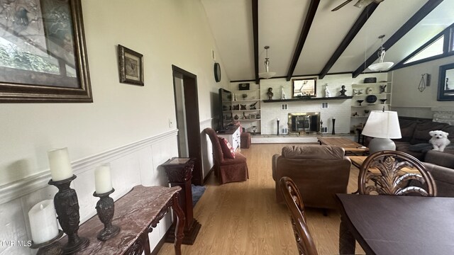 living room featuring vaulted ceiling with beams and light hardwood / wood-style flooring