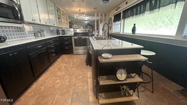 kitchen with sink, a breakfast bar area, decorative backsplash, a kitchen island with sink, and stainless steel appliances