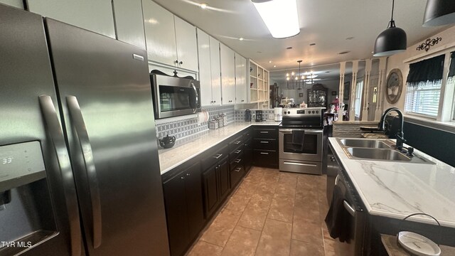 kitchen with white cabinetry, stainless steel appliances, sink, and hanging light fixtures