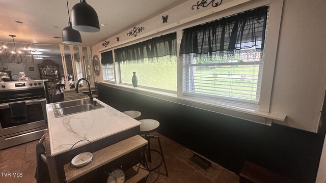 kitchen featuring tile patterned floors, decorative light fixtures, sink, and stainless steel electric range