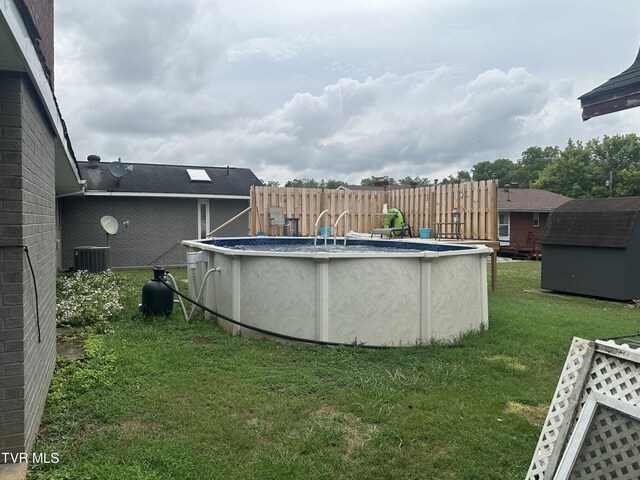 view of yard featuring cooling unit, a fenced in pool, and a shed