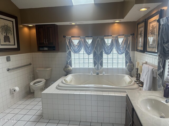 bathroom featuring toilet, tile walls, vanity, a relaxing tiled tub, and tile patterned flooring