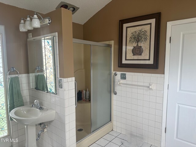 bathroom with tile walls, an enclosed shower, tile patterned floors, and a textured ceiling