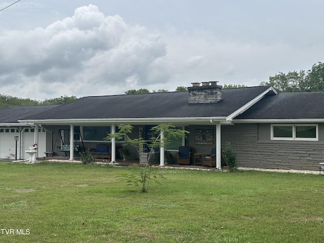 rear view of house featuring a garage and a yard