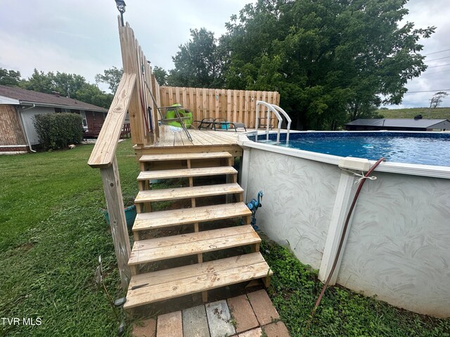 view of swimming pool featuring a lawn and a deck