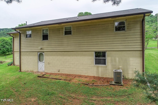 back of property featuring central AC and a lawn