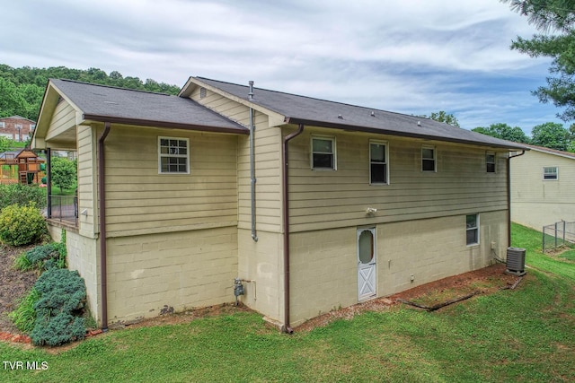 back of property featuring a lawn and cooling unit