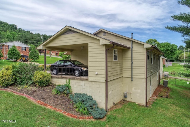 view of side of property with a yard, central AC unit, and a carport