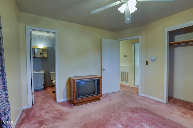 carpeted bedroom featuring connected bathroom, ceiling fan, and a closet